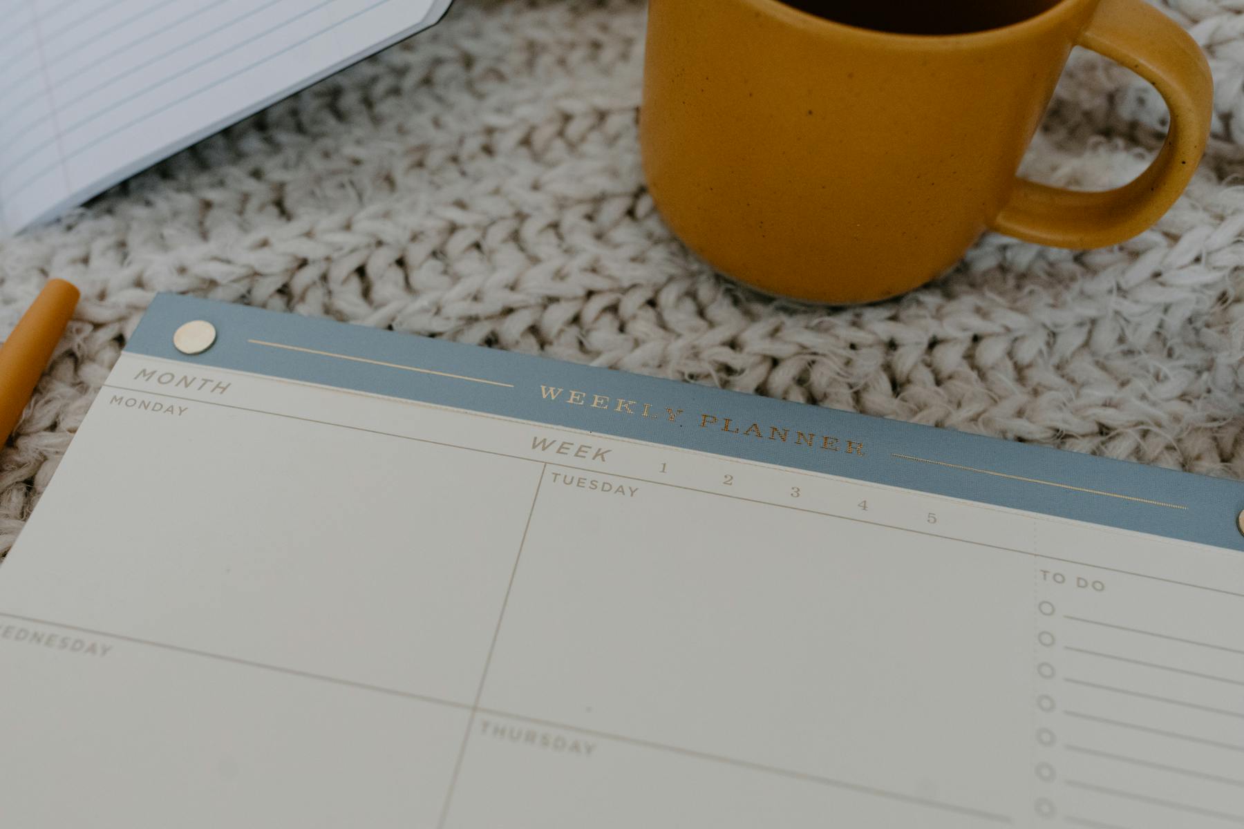 A weekly paper planner laid open beside a cup of coffee